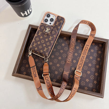 A brown iPhone case with a gold pattern and a matching brown strap with gold lettering.